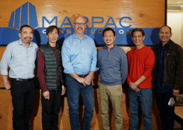 Members of the Marpac team stand in front of their business logo, smiling.