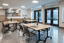 A community space at Kent Supportive Housing features a row of cabinets and several tables with simple gray chairs.