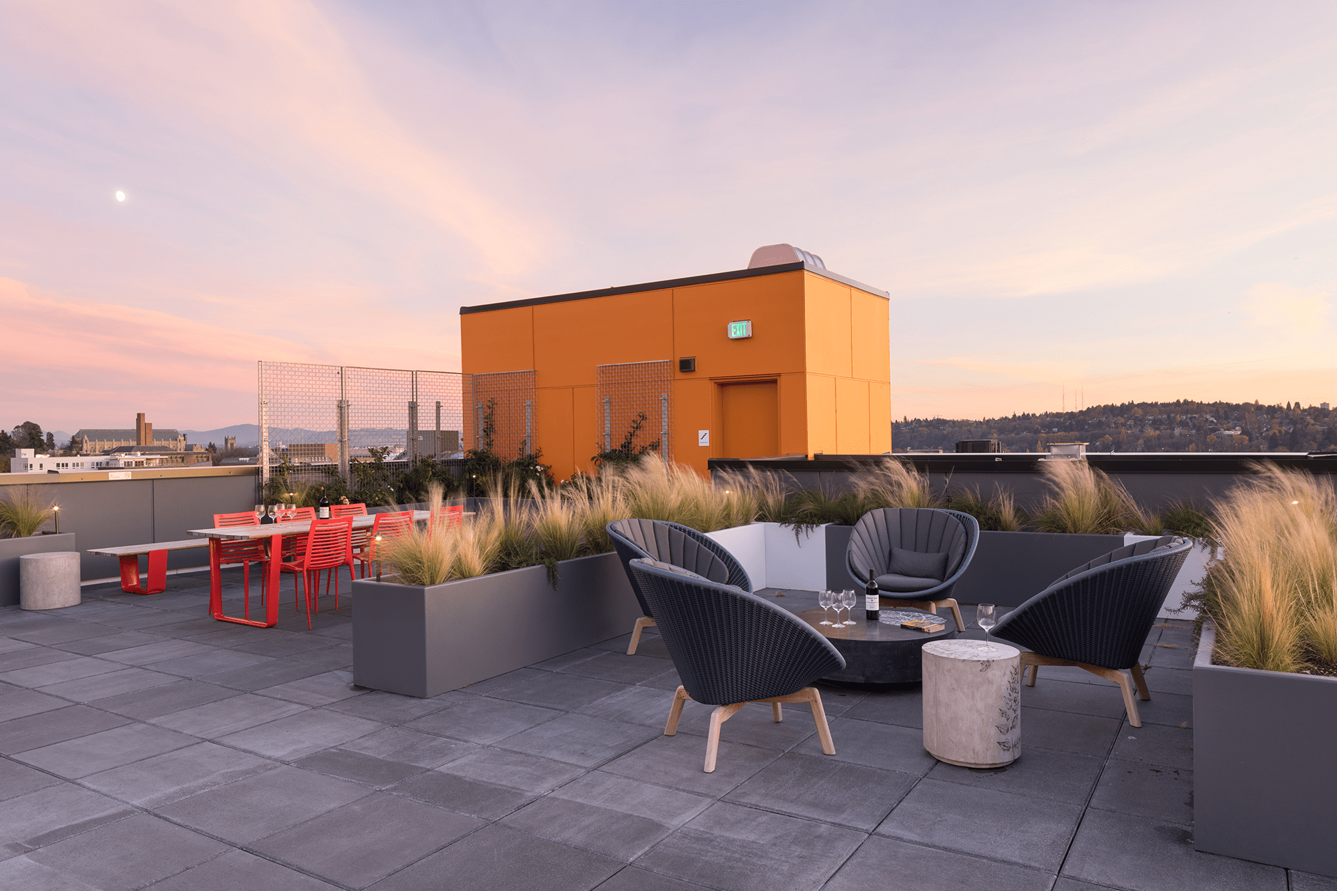 The top floor community space for the Roosevelt Apartments features multiple seating areas and a view of the city at dusk.