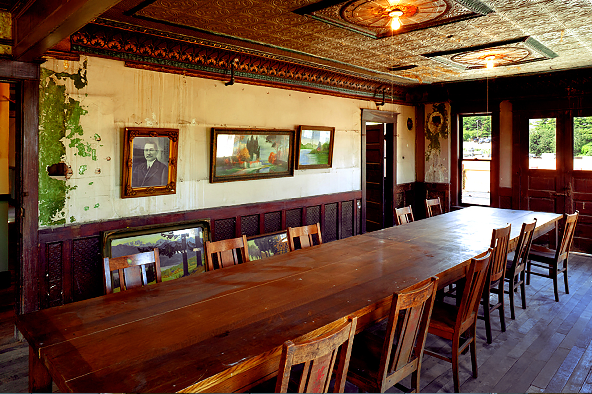 An exhibit at the Wing Luke Museum features framed photographs on the walls, a long wood table, and an ornate ceiling.