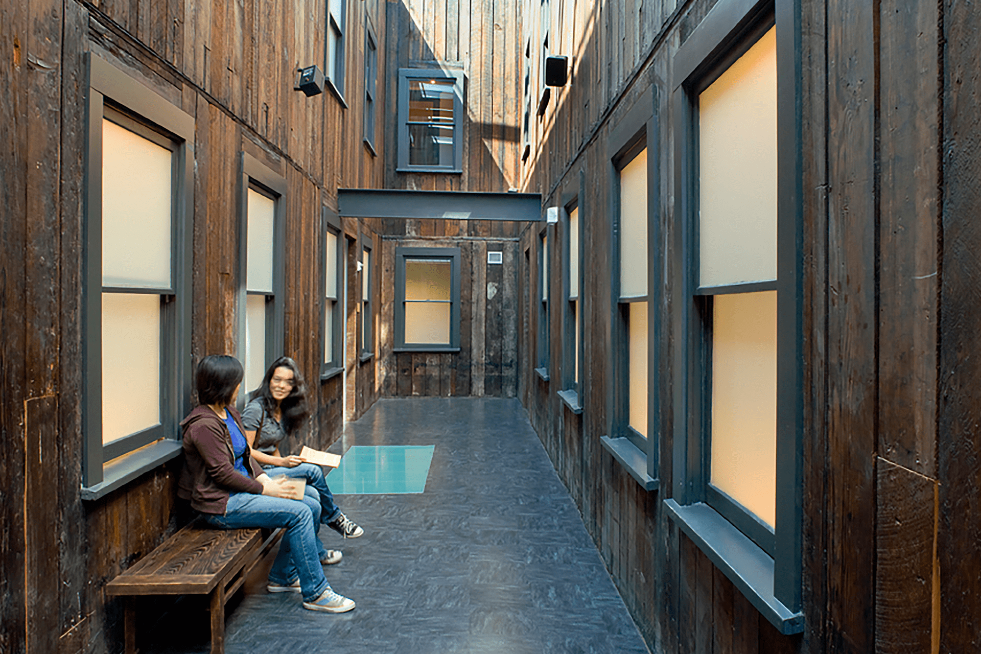 An interior courtyard at the Wing Luke Museum features dark wood siding, black-trimmed windows, and a place to sit.