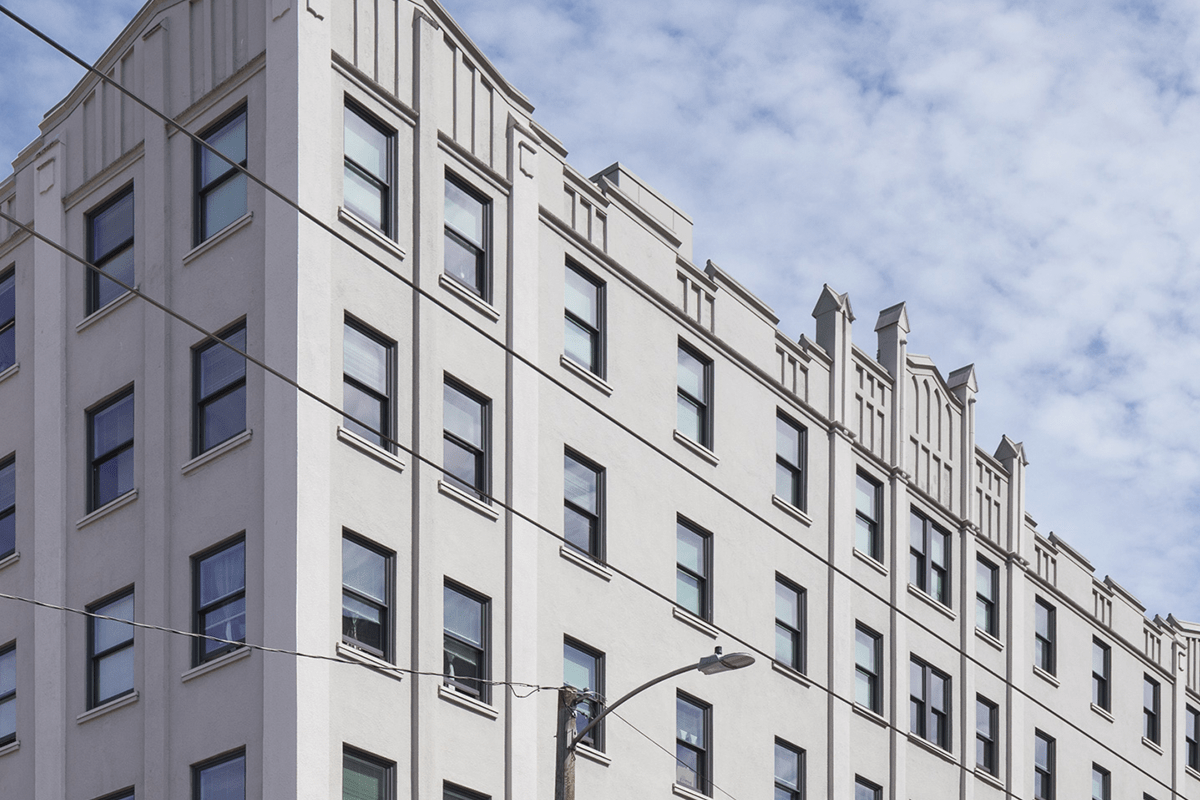 A close shot of some of the pointed architectural detail of the Publix Hotel, a gray building with evenly spaced windows on each of its six floors.